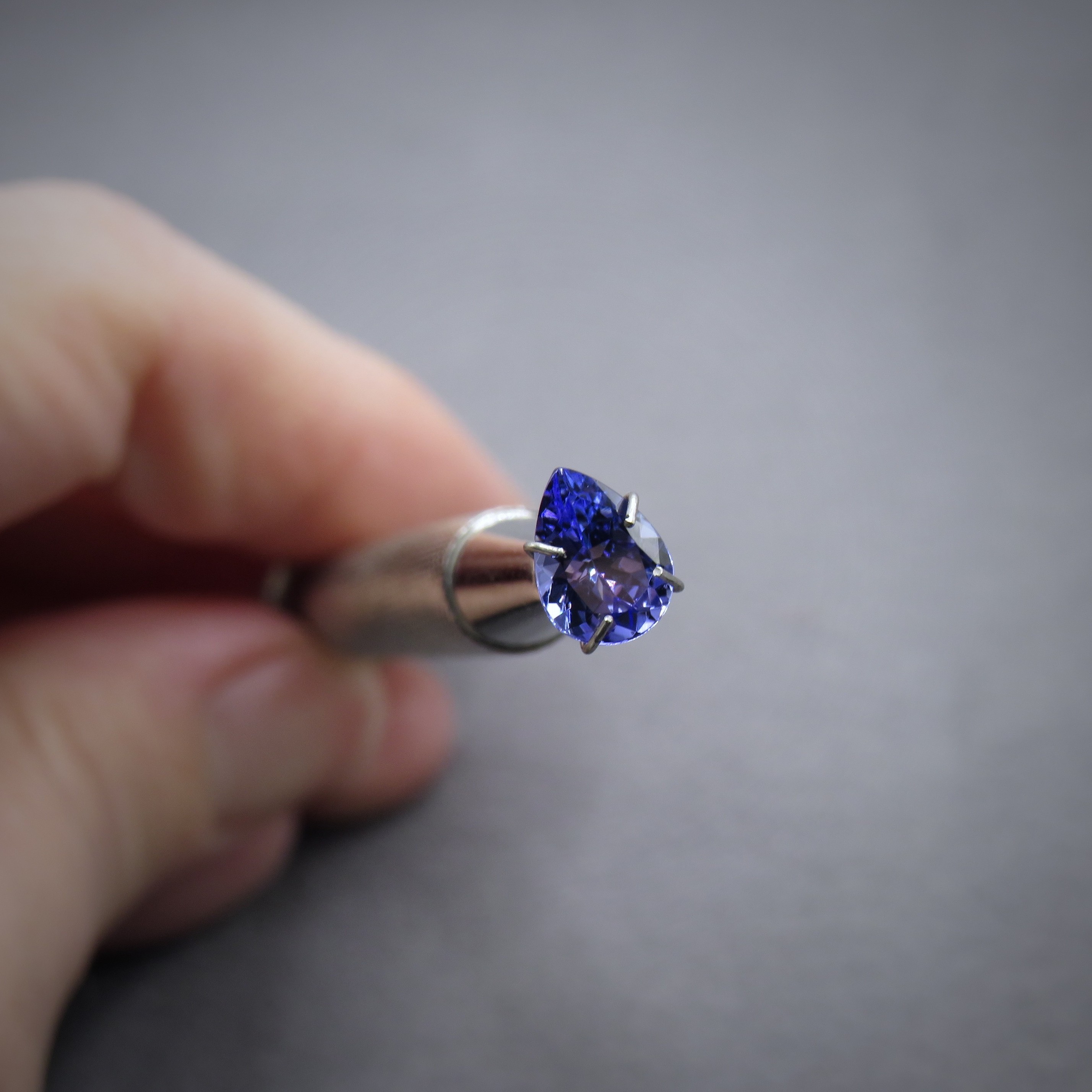 Pear tanzanite held in tweezers